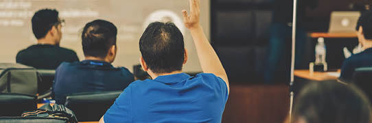 Rear view of Audience showing hand to answer the question from Speaker on the stage
