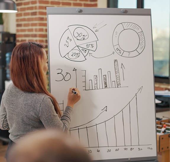 Diverse team of workmates discussing business growth, pointing at financial statistics on graphs in startup office. People analyzing management information on presentation in boardroom.