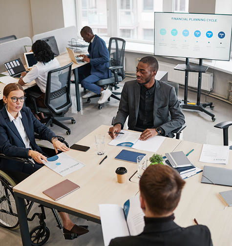 Portrait of smiling businesswoman using wheelchair while speaking at business meeting in office, copy space