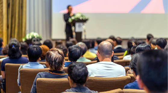 Back side of audience listening the Speaker with podium on the stage in the conference hall
